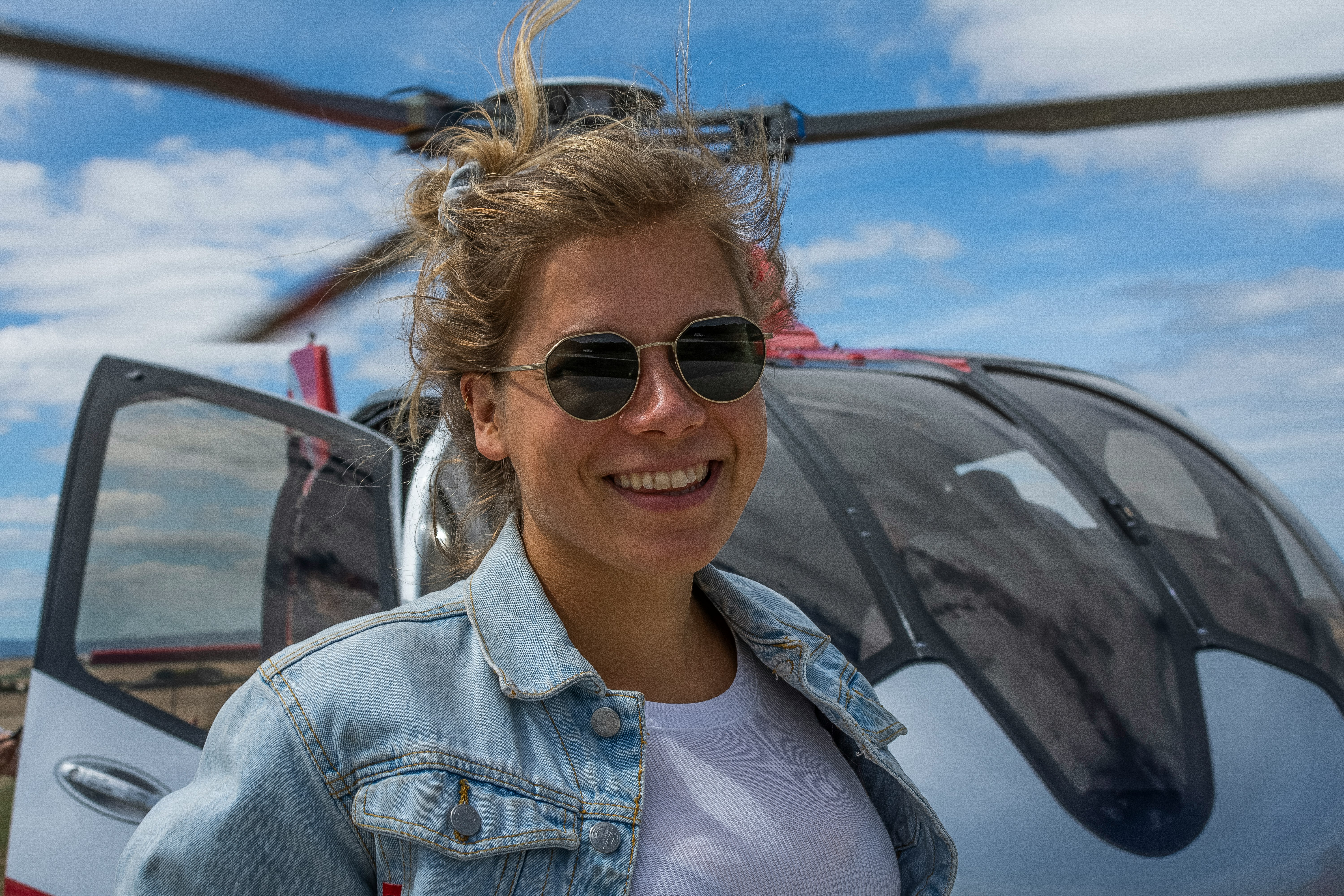 woman smiling in front of helicopter